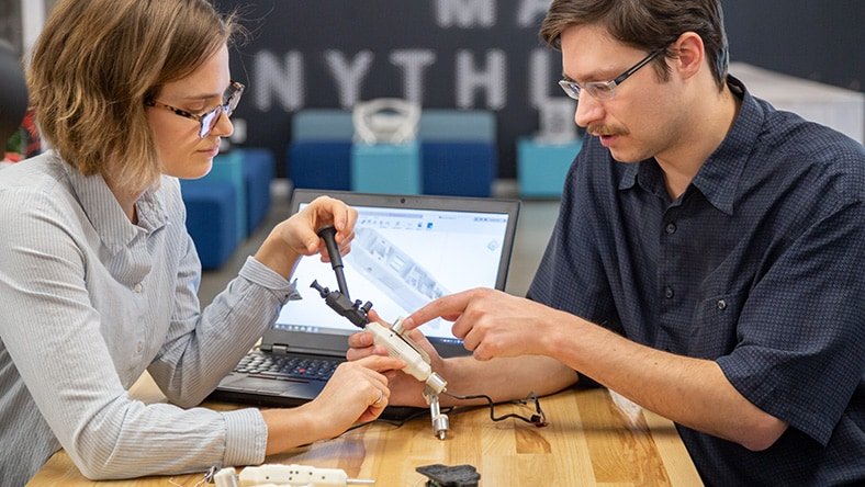 Equipo de ingeniería comparando un mecanismo físico con su modelo digital