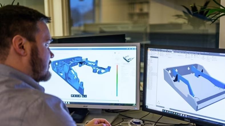 Ingeniero comparando geometría analizada y un modelo CAD en dos pantallas